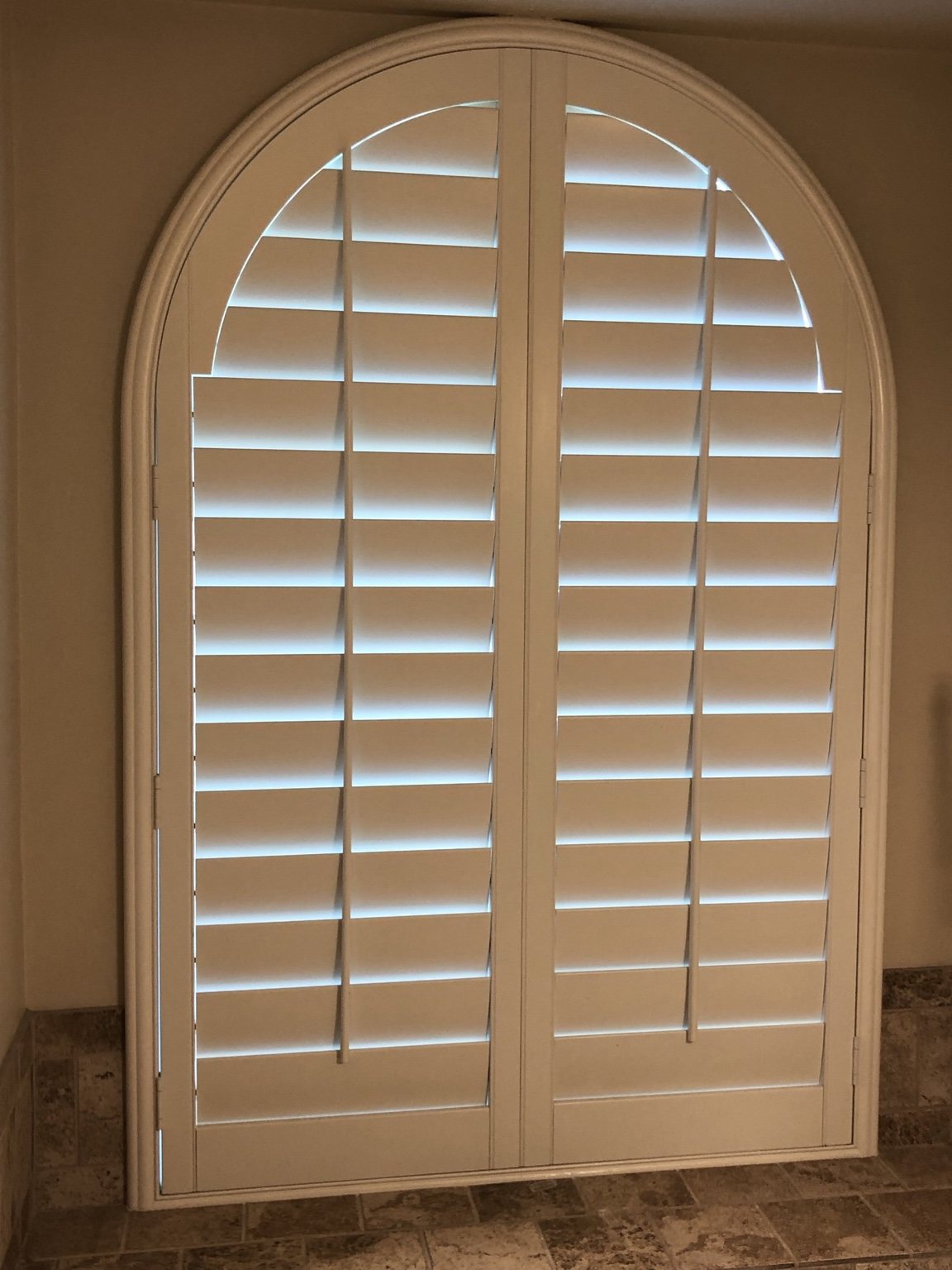 Custom arched plantation shutters on a specialty window
